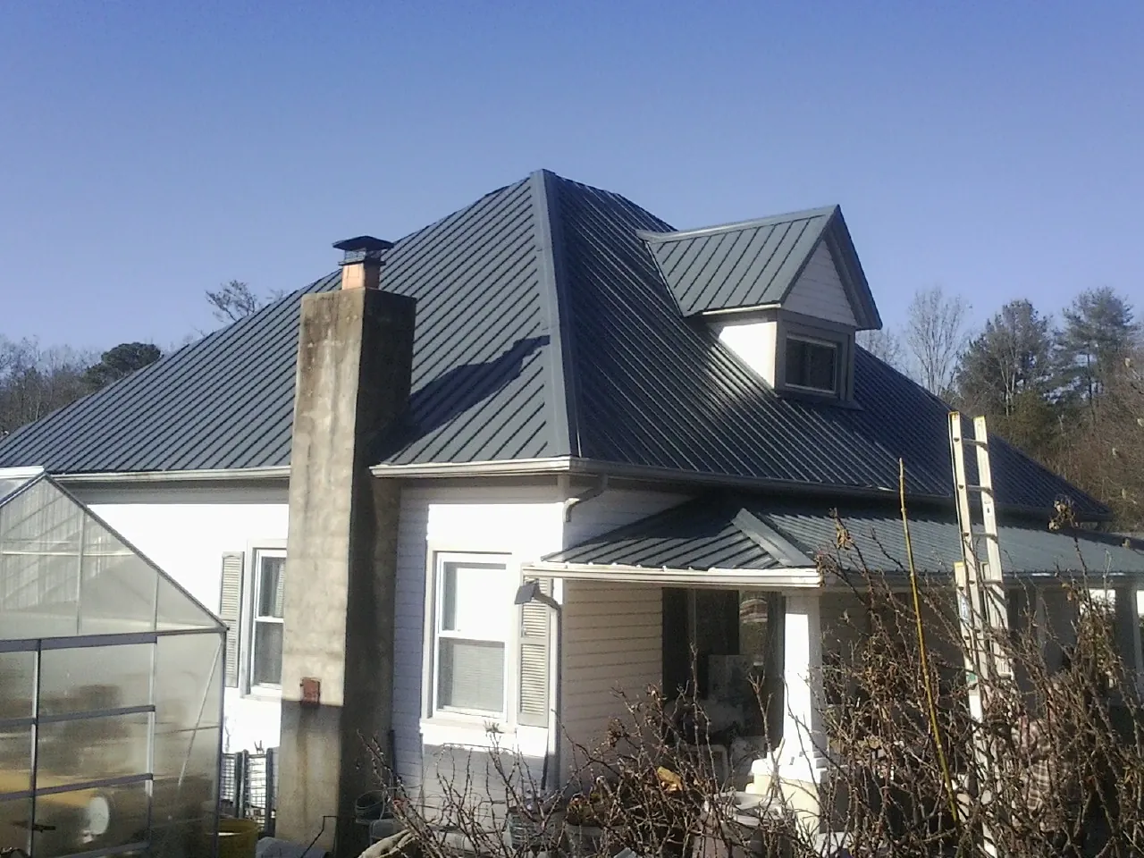Dark blue standing seam metal roof on a white farmhouse with dormer — Slate & Tile Roof Repair by Roofing Brothers in Theresa