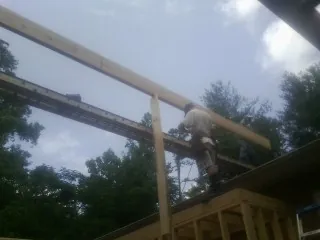Carpenter setting a ridge beam over a new addition frame — Ice Dam Removal by Roofing Brothers in Theresa