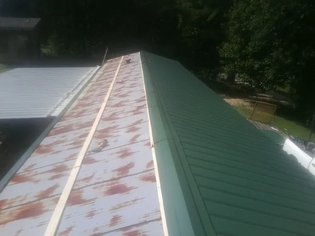 Old rusted panels beside newly installed green metal roofing — Wind Damage Roof Repair by Roofing Brothers in Theresa