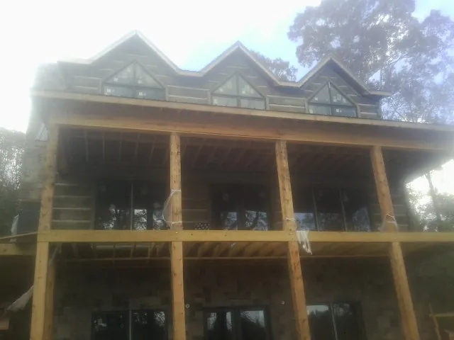 Dormers and porch framing on a large log home under construction — Roof Coating work by our crew in Theresa