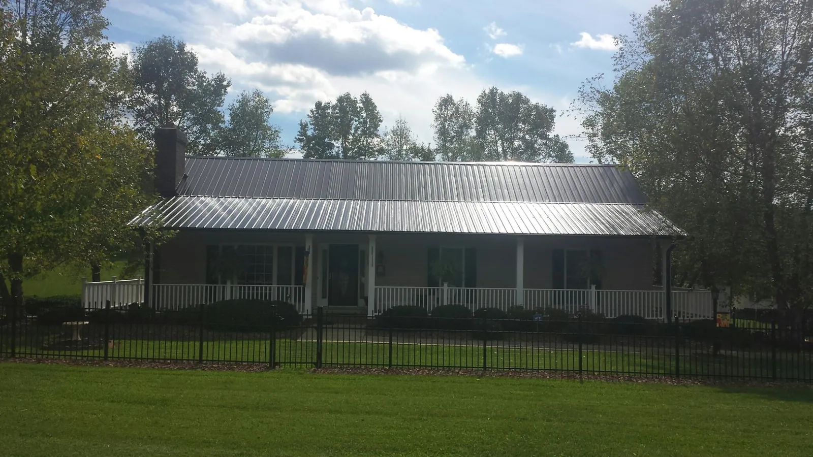 Gray metal roof on a brick ranch with a full width front porch — Gutter Guard Installation work by our crew in Theresa