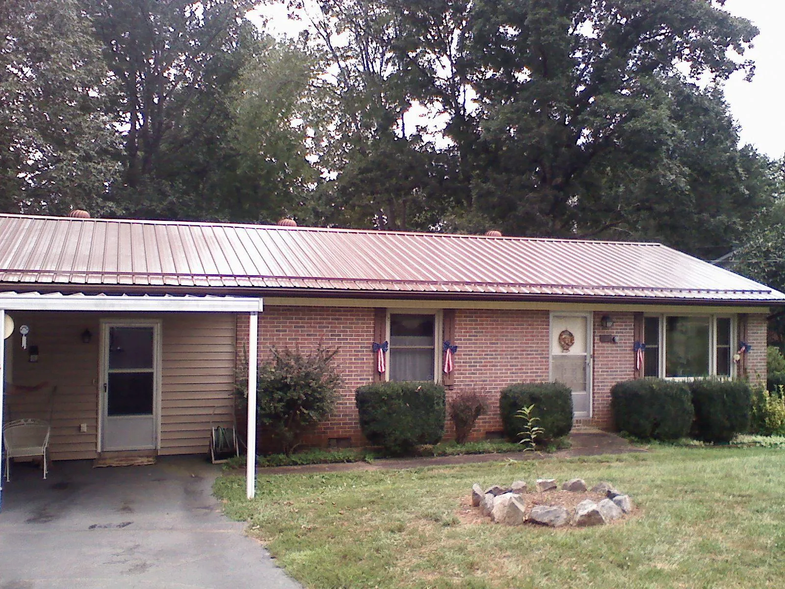 Bronze metal roof and carport on a brick ranch home — Roof Repair work by our crew in Theresa